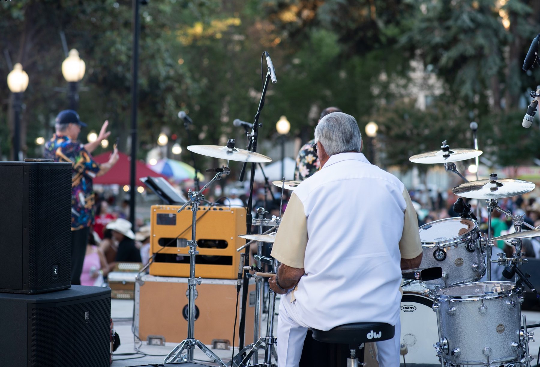 Behind-stage view of Ruben Ramos during the Tejano Conjunto Festival with drums, speakers and the Sacramento crowd beyond